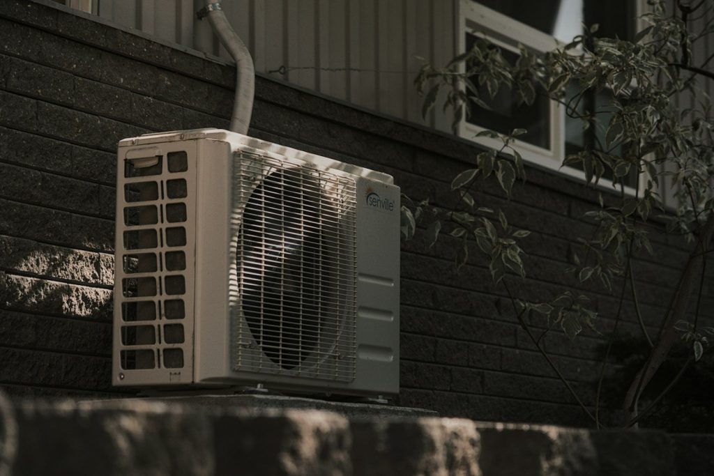 a white air conditioner sitting on top of a brick wall for AIr Conditioning Services in Mexico Beach, FL