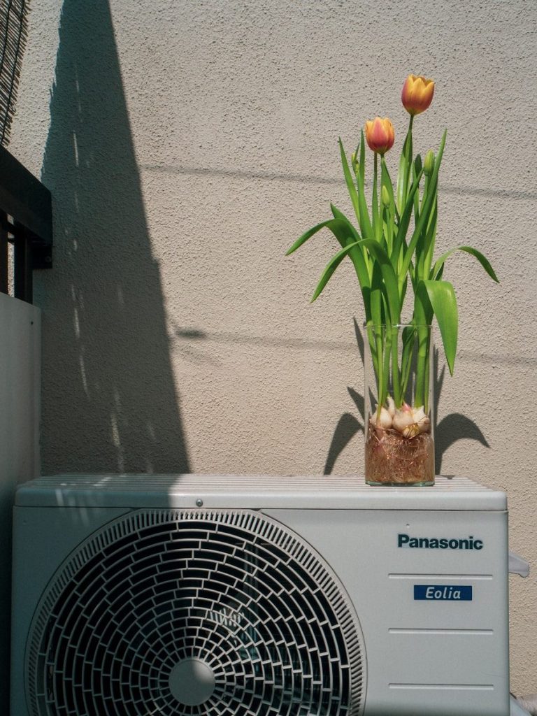 a small air conditioner sitting next to a flower pot during Heating & HVAC System Installation in Santa Rosa Beach, FL