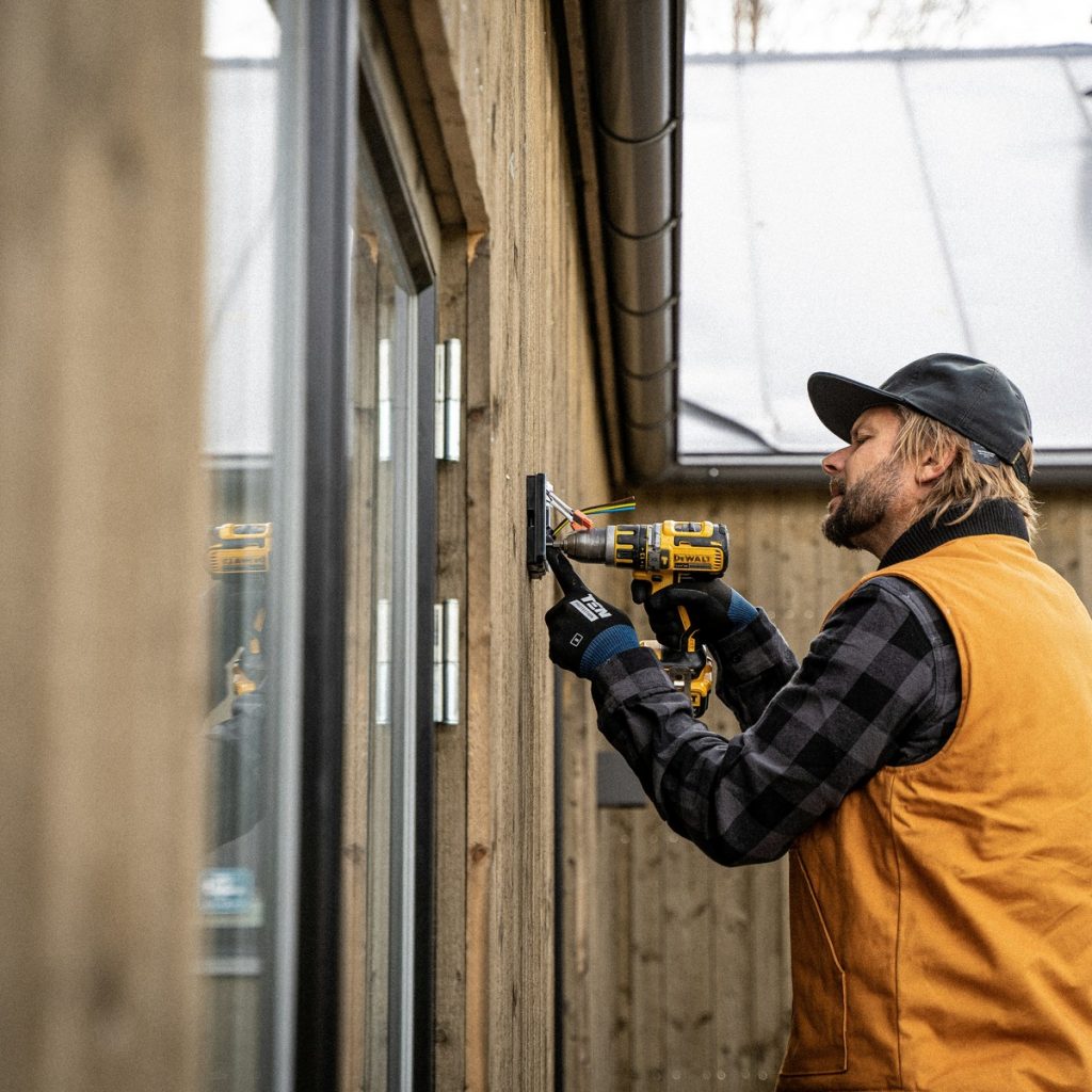 A uniformed technician mounting and wiring a new heating unit during professional Heating and HVAC System Services in Youngstown, FL.